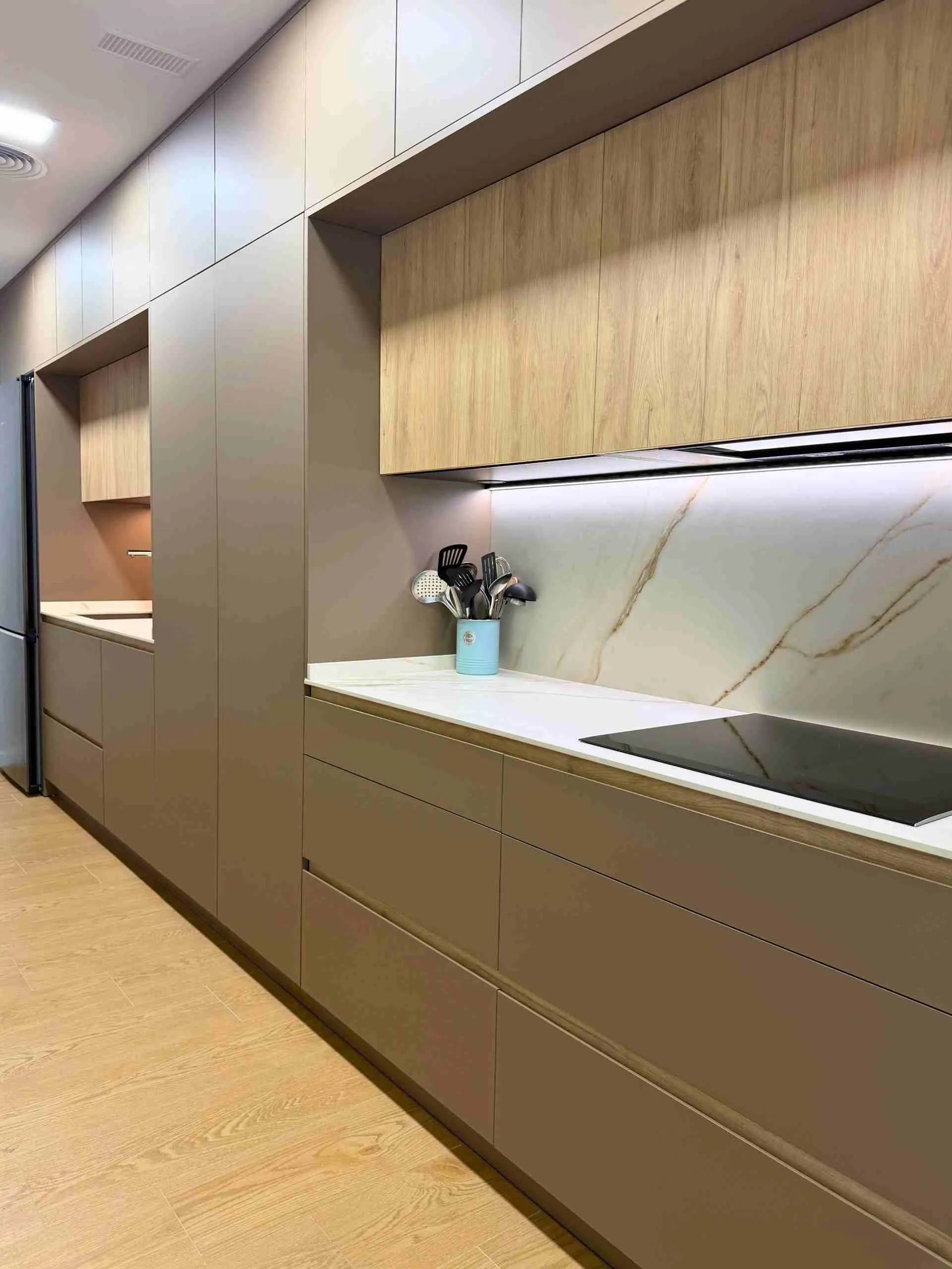 placa de inducción en cocina lineal con despensero de puertas escamoteables